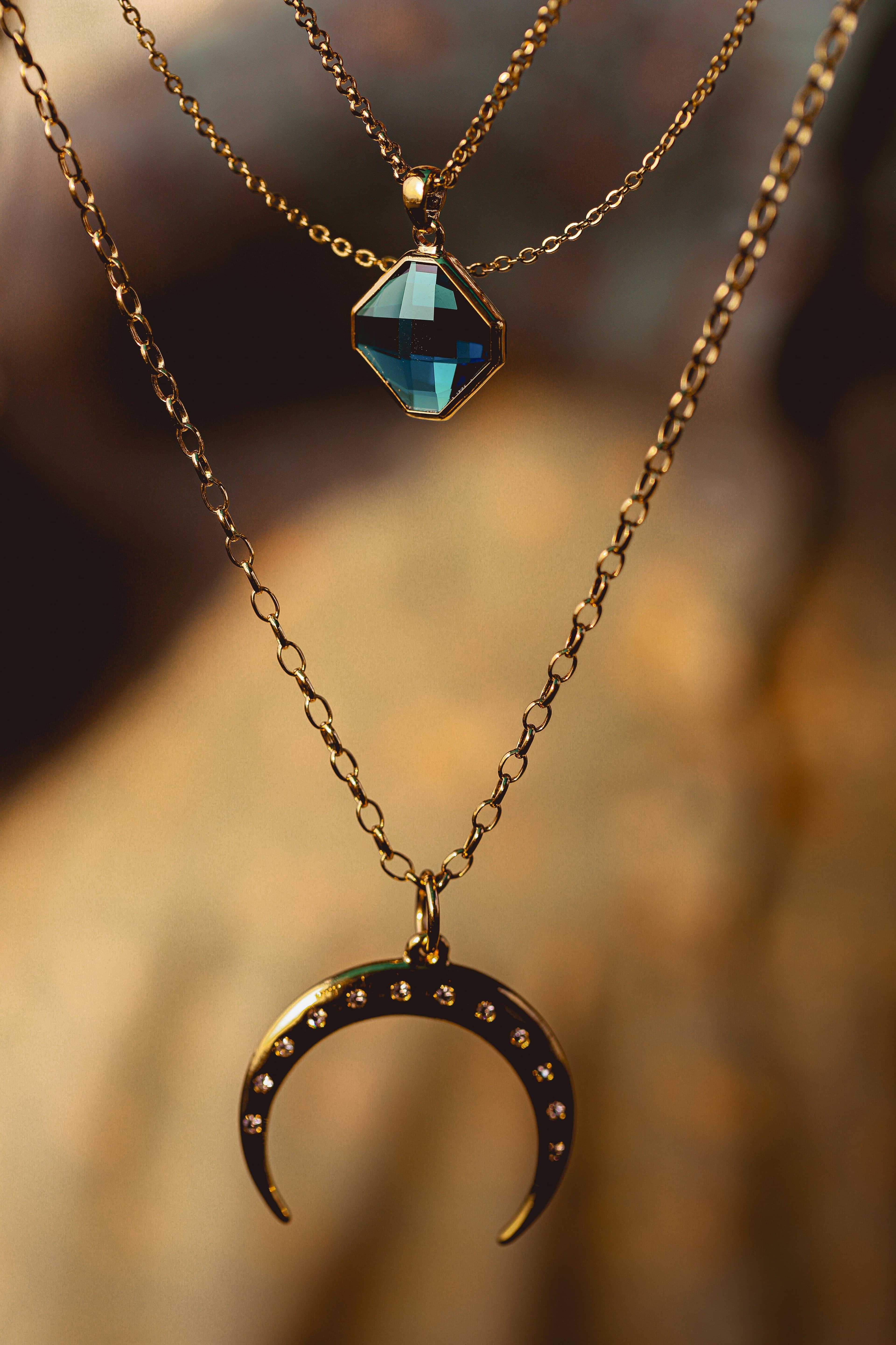 A gold pendant on fine chains under warm light