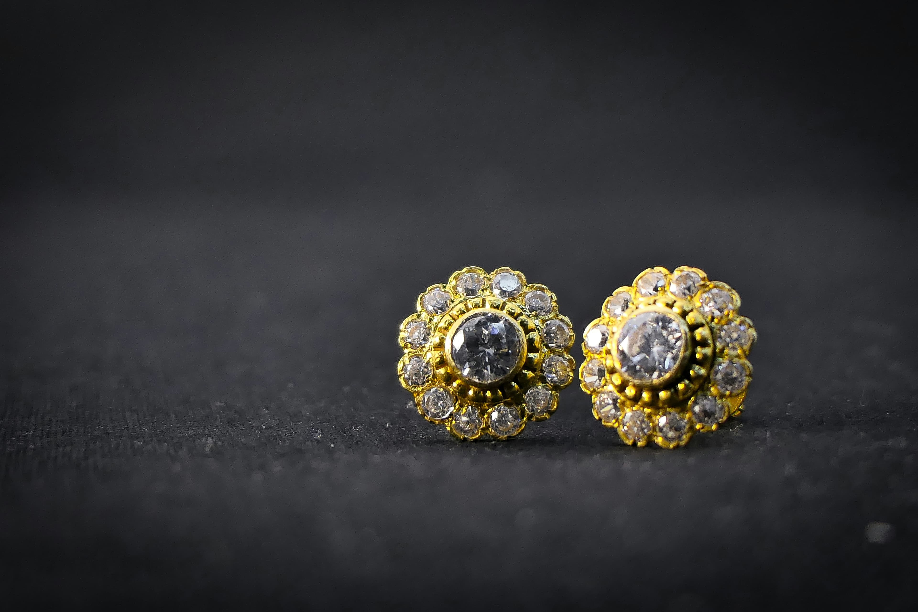Gold and diamond flower earrings on a dark counter
